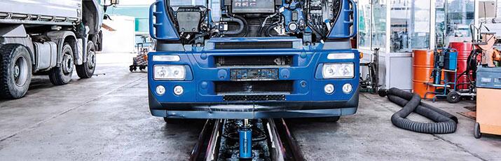 Blauer Lkw in Frontansicht in der Werkstatthalle.