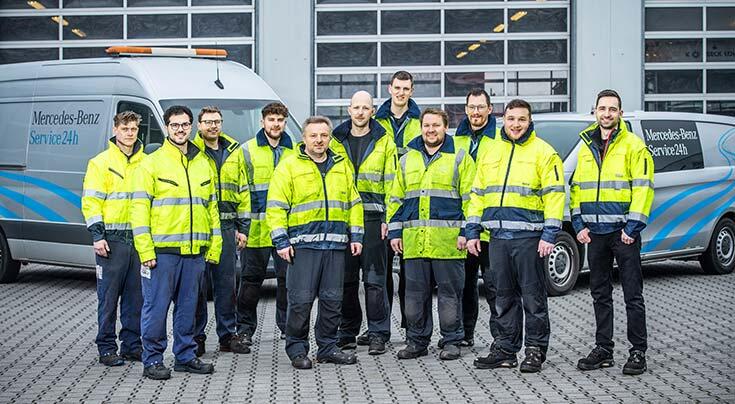 Autohaus Ewald Menke Serviceteam vor zwei Servicefahrzeugen, im Hintergrund die Werkstatthalle.