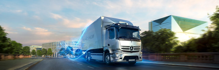 Fahraufnahme eines Mercedes-Benz eActros, im Hintergrund Bäume und Gebäude.